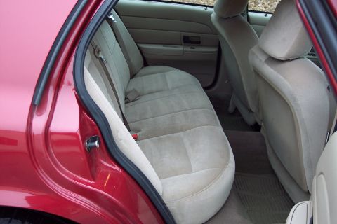2001 Ford Crown Victoria - Rear interior view of a 2001 Ford Crown Victoria, showing tan cloth seats and red exterior paint.