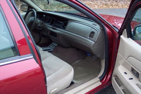2001 Ford Crown Victoria - The interior of a red 2001 Ford Crown Victoria is shown with the driver's side door open.