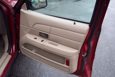 2001 Ford Crown Victoria - Interior view of a red car's driver's side door panel, showing tan trim and controls.