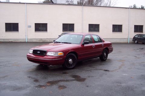 2001 Ford Crown Victoria - A red 2001 Ford Crown Victoria is parked outside a commercial building.