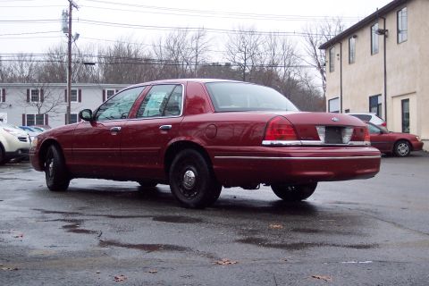 2001 Ford Crown Victoria - Rear view of a red 2001 Ford Crown Victoria parked outside on a wet day.