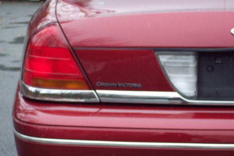 2001 Ford Crown Victoria - Rear view of a red 2001 Ford Crown Victoria, its distinctive taillights and chrome accents.