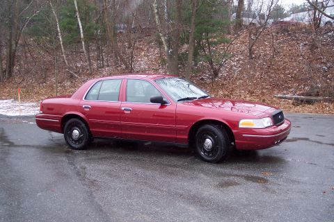 2001 Ford Crown Victoria - Red 2001 Ford Crown Victoria sedan parked outdoors on a cloudy day.