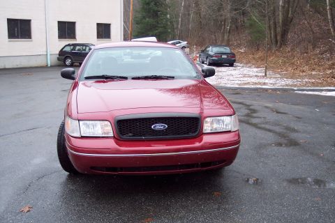 2001 Ford Crown Victoria - Front view of a red 2001 Ford Crown Victoria parked in a lot with another vehicle visible in the background.