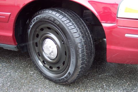 2001 Ford Crown Victoria - The front passenger side wheel and fender of a red 2001 Ford Crown Victoria are shown in this close-up photograph.