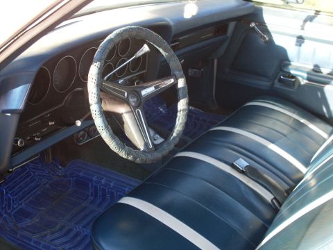 1972 Ford Ranchero - The interior of a classic car features striped blue seats and a dashboard with multiple gauges.
