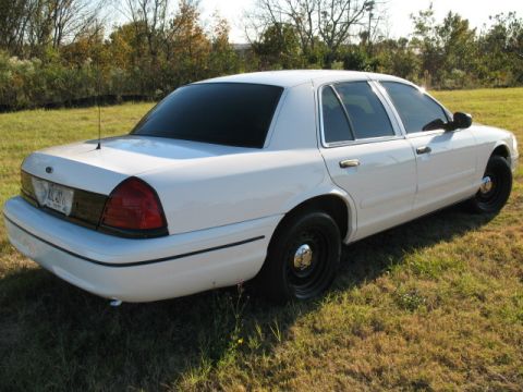 2000 Ford Crown Victoria - This white 2000 Ford Crown Victoria is shown from the rear three-quarter angle, parked on a grassy area.
