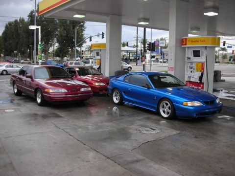 1998 Ford Crown Victoria - Three cars, including a Crown Victoria and a Mustang Cobra, are parked at a gas station.