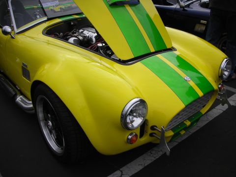 1998 Ford Crown Victoria - A yellow sports car with green racing stripes is parked with its hood open, revealing the engine compartment.