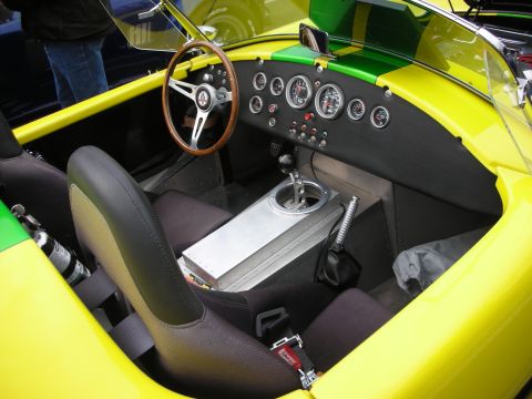 1998 Ford Crown Victoria - The interior of a vibrant yellow and green race car features racing seats, a wood-rimmed steering wheel, and a dashboard filled with gauges.