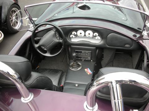 1998 Ford Crown Victoria - The interior of a custom roadster features a dashboard and comfortable seating, with another vehicle parked nearby.