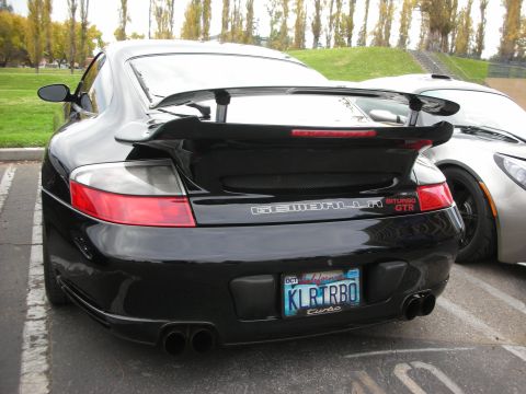 1998 Ford Crown Victoria - A black Gemballa Biturbo GTR is parked next to another vehicle, its distinctive rear spoiler and quad exhaust pipes.