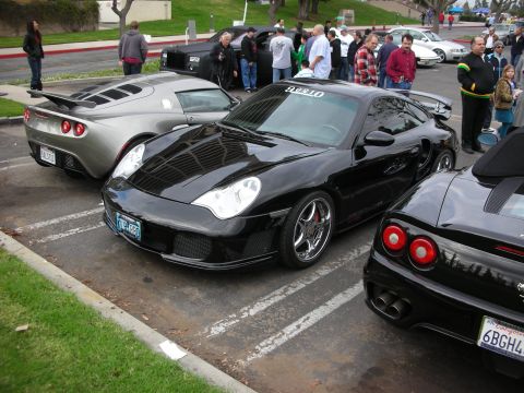 1998 Ford Crown Victoria - Several sports cars are parked in a lot, with a black Porsche 911 in the foreground.