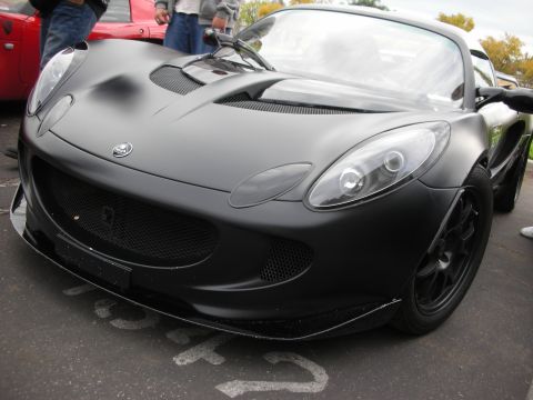 1998 Ford Crown Victoria - A matte black Lotus Elise is parked in front of a red car.