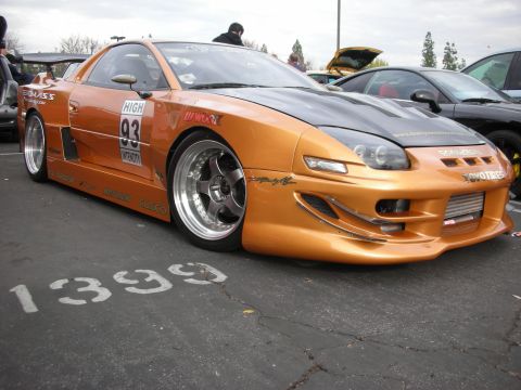 1998 Ford Crown Victoria - Modified orange sports car with racing decals and aftermarket wheels parked on asphalt.