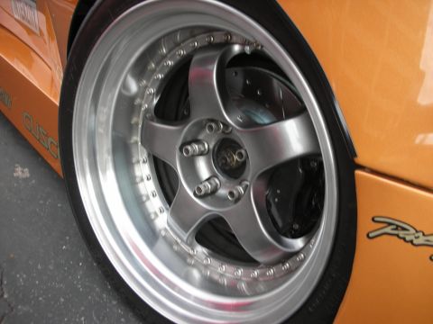 1998 Ford Crown Victoria - A close-up view of a custom five-spoke wheel and brake assembly on an orange vehicle.