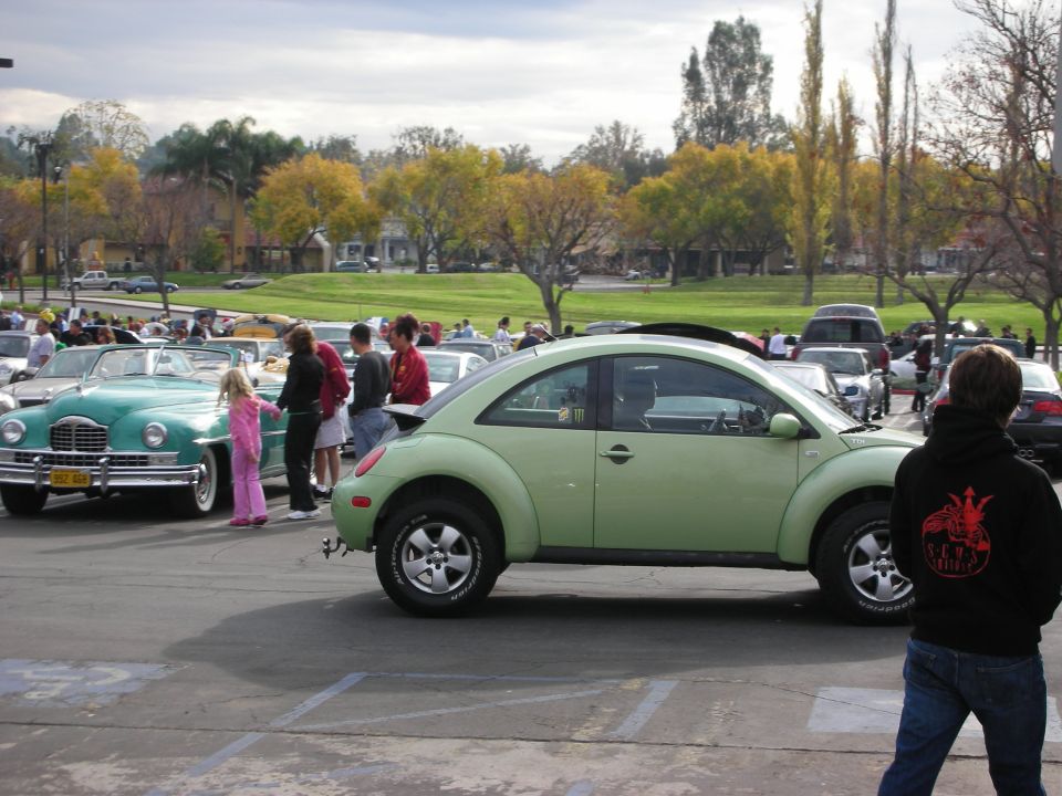 Light green Volkswagen Beetle, side view, parked at an outdoor event
