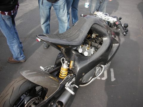 1998 Ford Crown Victoria - A custom sport motorcycle with a carbon fiber body and visible engine parts is displayed outdoors.