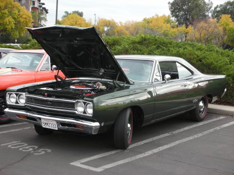 1998 Ford Crown Victoria - 1969 Plymouth GTX parked with hood up, showing engine bay. Another car is visible to the left.