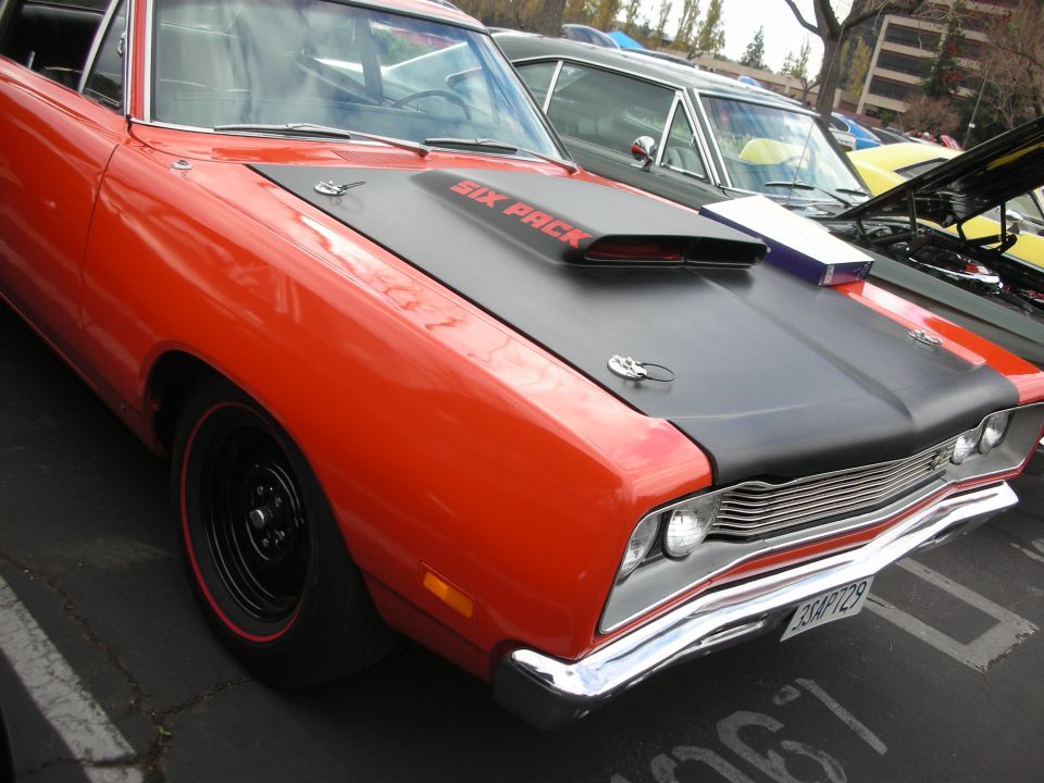 Orange 1969 muscle car with black hood scoop reading "SIX PACK"