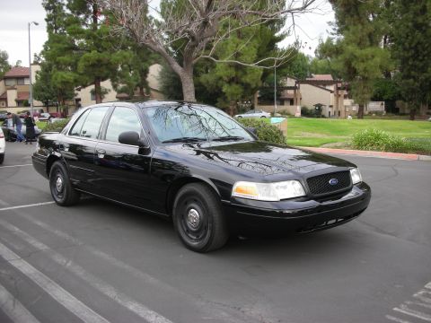 1998 Ford Crown Victoria - 1998 Ford Crown Victoria parked in a lot with trees and buildings in the background.
