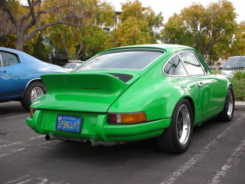 1998 Ford Crown Victoria - A bright green Porsche 911 Carrera RS is parked in a lot, with a blue car to its left.