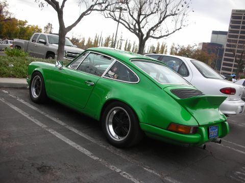 1998 Ford Crown Victoria - A bright green Porsche 911 is parked in a lot next to other vehicles.