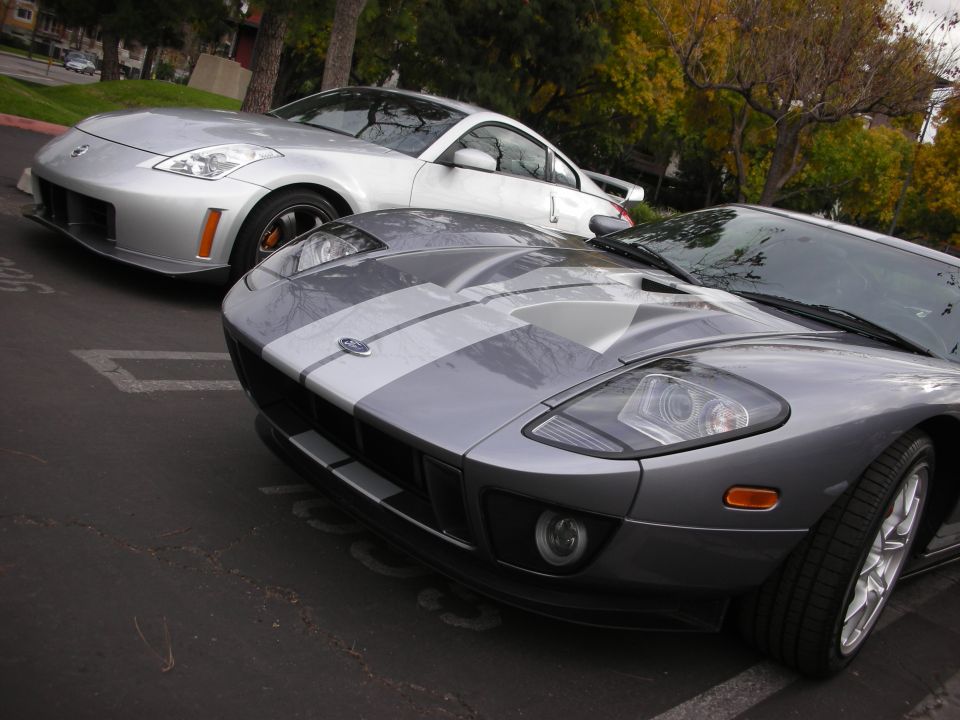 Silver Ford GT with racing stripes and a silver Nissan 350Z parked side-by-side