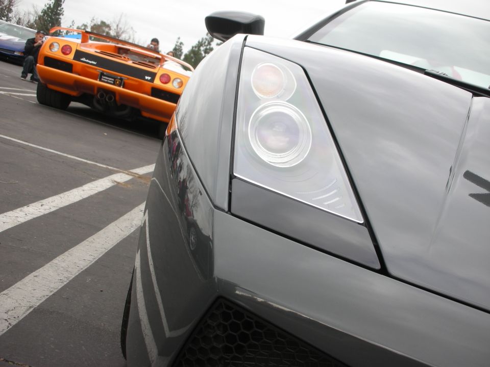 Lamborghini Gallardo headlight closeup with orange McLaren F1 behind