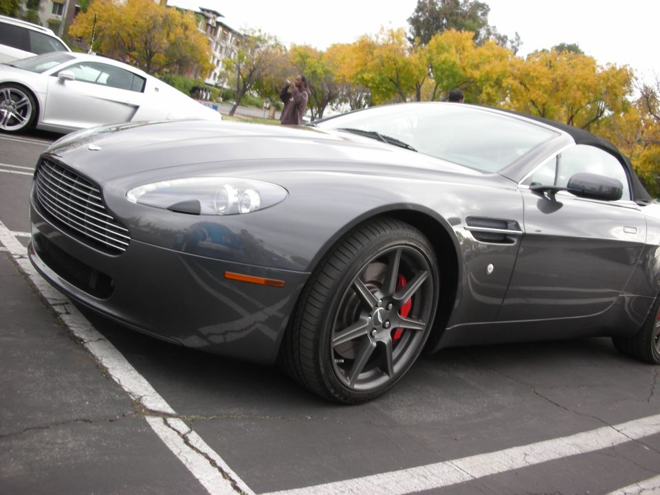 Gray sports car rear quarter panel and wheel, parked in a lot