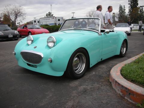 1998 Ford Crown Victoria - A teal convertible sports car is parked outside, with other vehicles in the background.