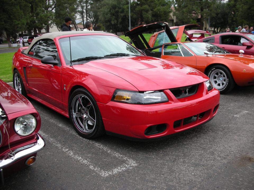 Red convertible sports car with hood scoop and aftermarket wheels