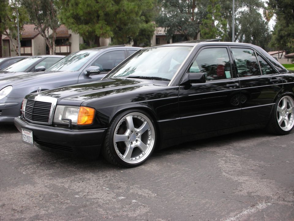 Black Mercedes-Benz 190E with custom wheels parked next to another car
