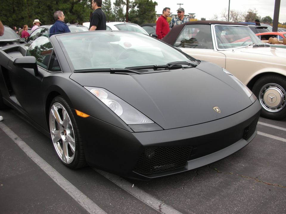 Black convertible sports car parked next to a cream-colored classic car