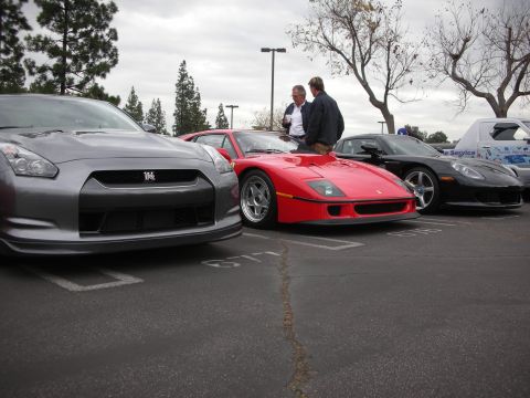 1998 Ford Crown Victoria - A gathering of performance vehicles, a Ferrari, Nissan GT-R, and Corvette, parked outdoors.