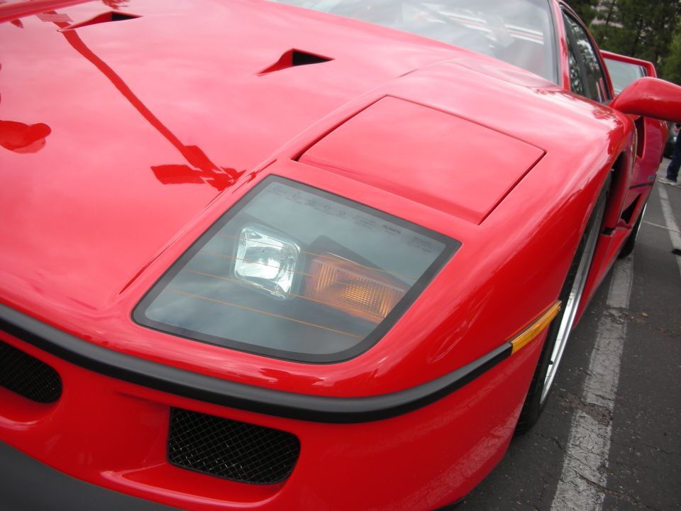 Close-up of a red sports car's front end, showing the pop-up headlight and grille