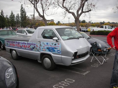 1998 Ford Crown Victoria - A silver customized pickup truck is parked in a lot with other vehicles and trees in the background.