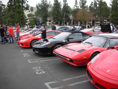 1998 Ford Crown Victoria - A gathering of sports cars, including Ferraris, parked in a lot with spectators present.