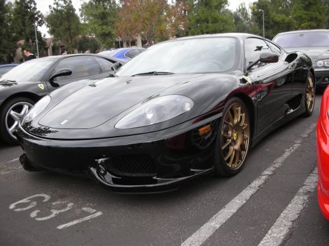 1998 Ford Crown Victoria - A black Ferrari 360 Modena is parked next to other vehicles in a lot.