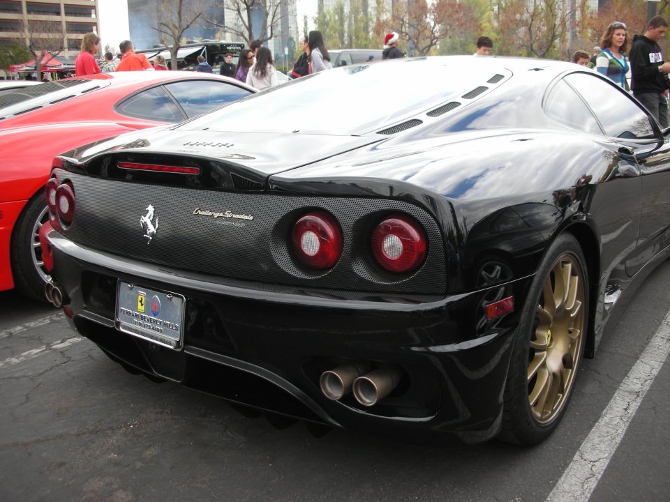 Black Ferrari 360 Challenge Stradale with gold wheels parked next to a red car