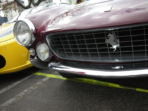 1998 Ford Crown Victoria - A close-up view of the front of a maroon Ferrari, parked next to a yellow car.