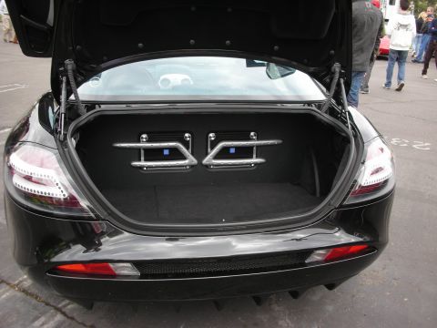 1998 Ford Crown Victoria - The trunk of a black sports car is open, revealing custom audio equipment and a carpeted storage area.