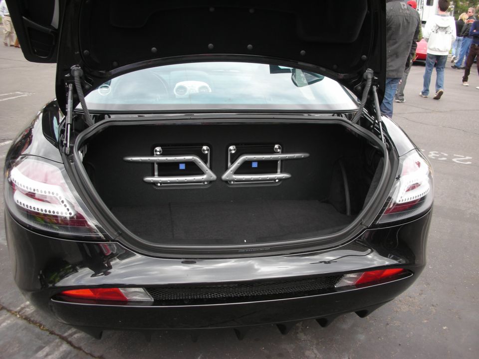 Black sports car trunk open, showing custom audio equipment mounted inside