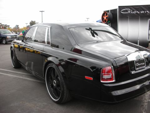 1998 Ford Crown Victoria - A black Rolls-Royce Phantom with custom rims is parked outdoors.