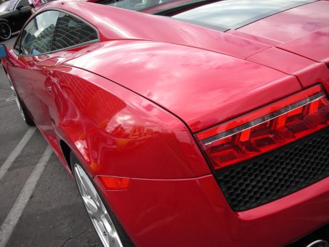 1998 Ford Crown Victoria - A red sports car is parked in a lot, showing its rear design and a reflection of buildings.