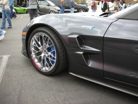 1998 Ford Crown Victoria - Close-up of a Chevrolet Corvette ZR1 fender and wheel, with other vehicles visible in the background.