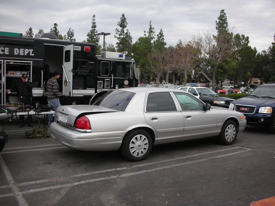 Silver sedan parked next to a police truck. Another SUV is to the right