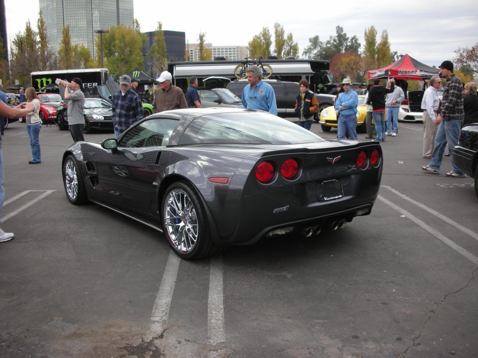 Dark gray Chevrolet Corvette with chrome wheels, quad exhaust pipes, and a rear spoiler