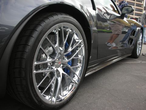 1998 Ford Crown Victoria - A detailed view of a shiny chrome wheel and blue brake caliper on a dark-colored vehicle.