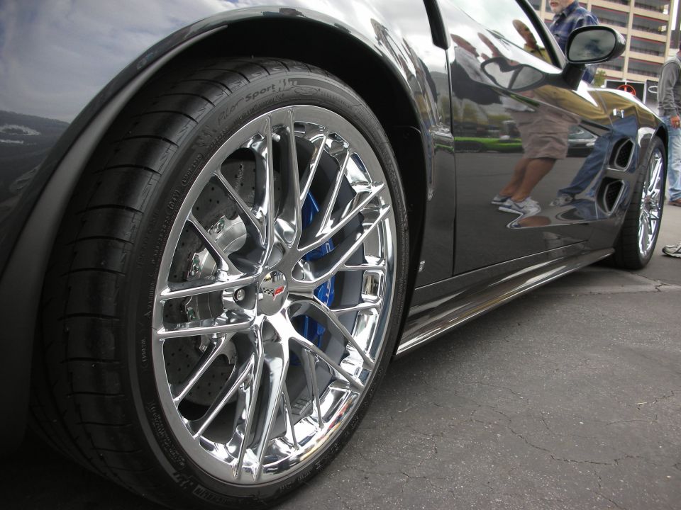 Close-up of a chrome wheel with blue brake calipers on a dark car